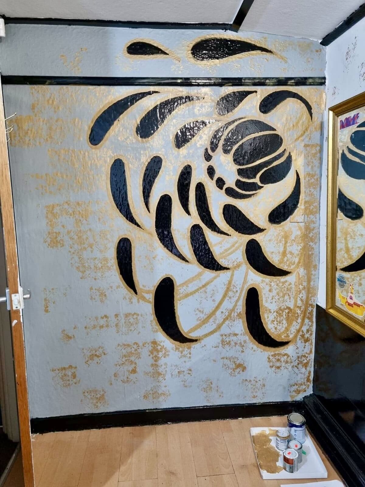 Interior wall mural with abstract black and gold shapes on blue-grey